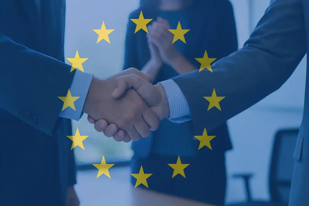 Dos ejecutivos estrechan la mano con estrellas de la Unión Europea superpuestas, simbolizando un acuerdo apoyado por los fondos Next Generation EU.